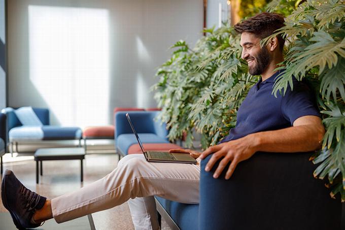 man sitting on chair smiling at laptop